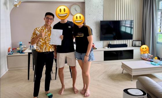 Wilfred with a couple in their living room, holding the signed sale agreement