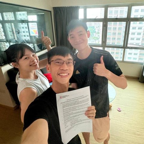 Wilfred with a young couple in their flat, holding the signed agreement